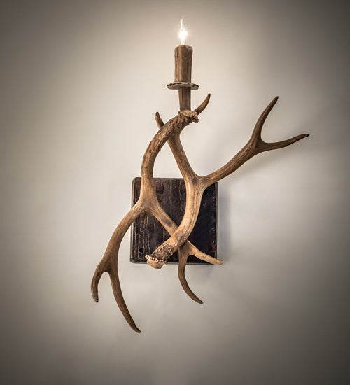 Elk antler wall sconce with natural shed antlers and candle style light in rustic lodge design