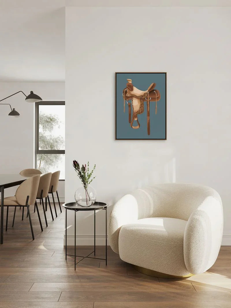 Modern living room with a white armchair, dining table, and western saddle art on the wall - Your Western Decor