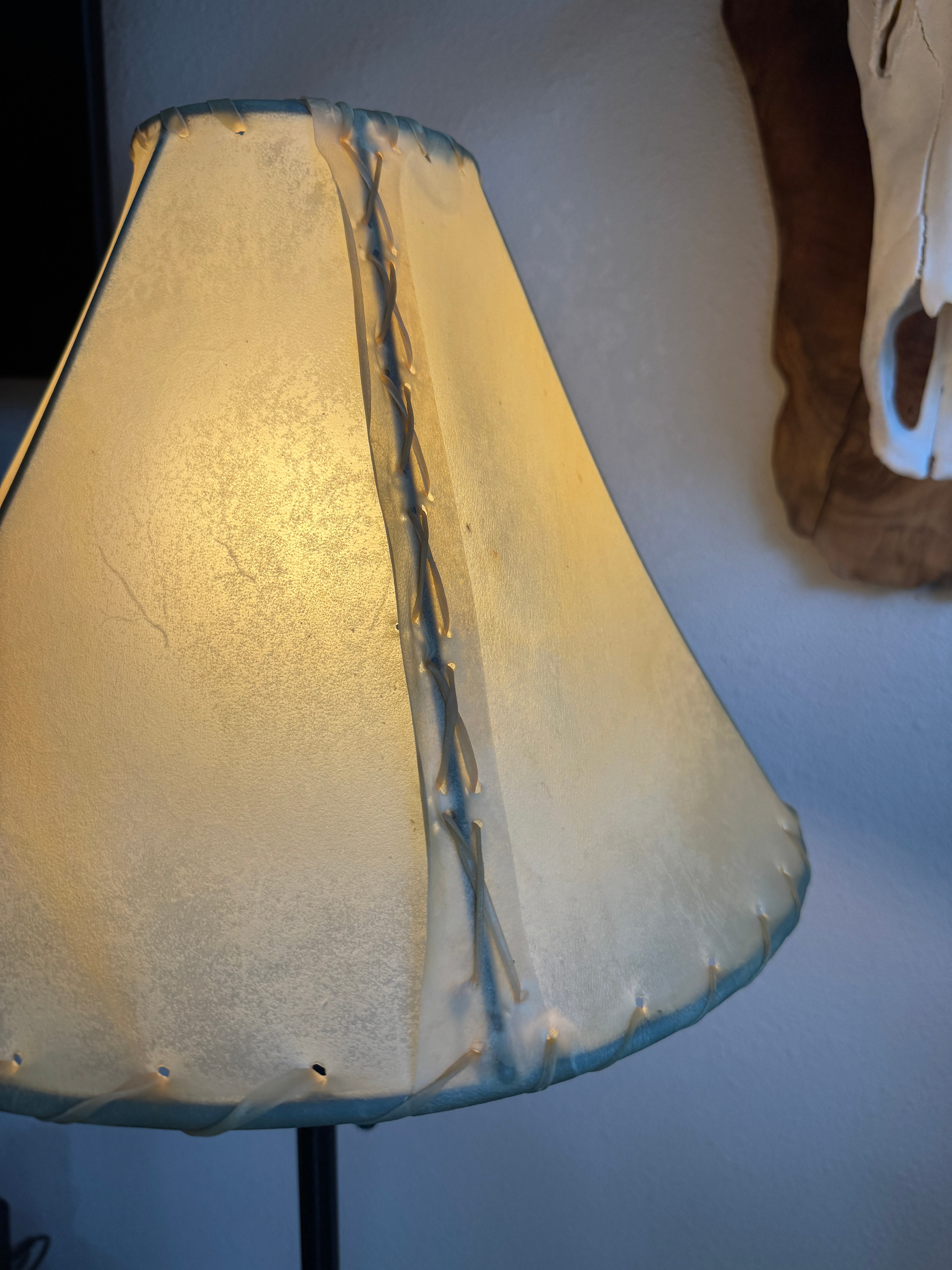 Whip stitch side of natural rawhide lamp shade with light on