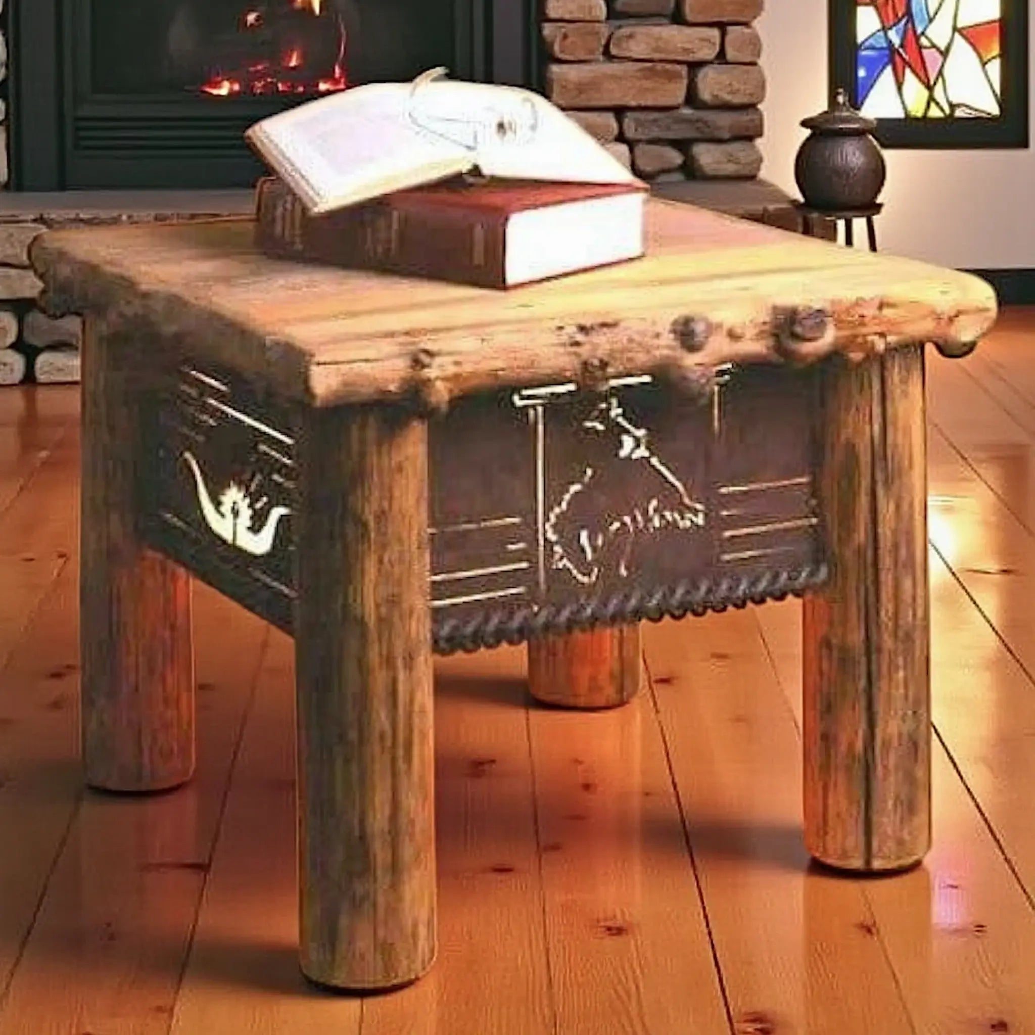 A rustic log-style end table with metal cutout bronc and western motifs, shown in a cozy room setting with a fireplace, books on top, and a wooden floor.