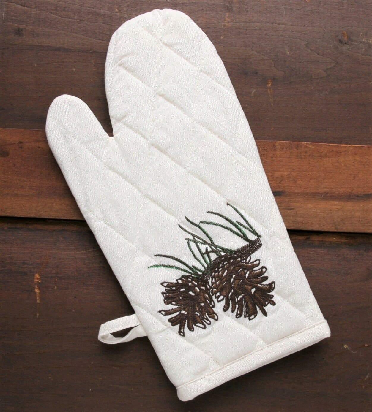 Embroidered pine cone kitchen oven mitts over ivory cotton. Your Western Decor