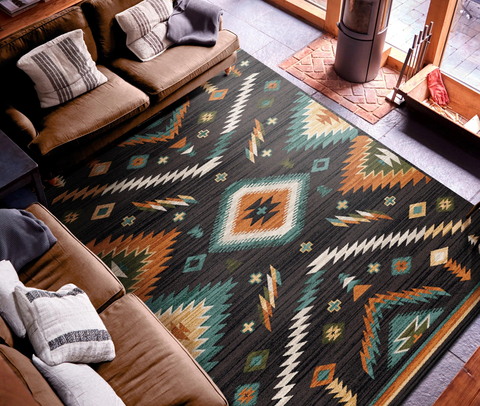 Geometric pattern area rug in greens, terra cotta, off-white over a charcoal background. In room with leather furniture 