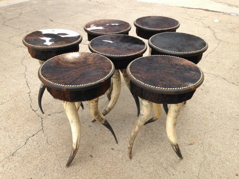 Side tables standing on steer horn legs with cowhide upholstered tops and nail trim 