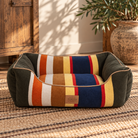 Pendleton Badlands striped bolster dog bed with navy, rust, mustard and olive tones in a rustic Western interior.