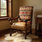 Decorative armchair with patterned backrest in a room with a window and side table.