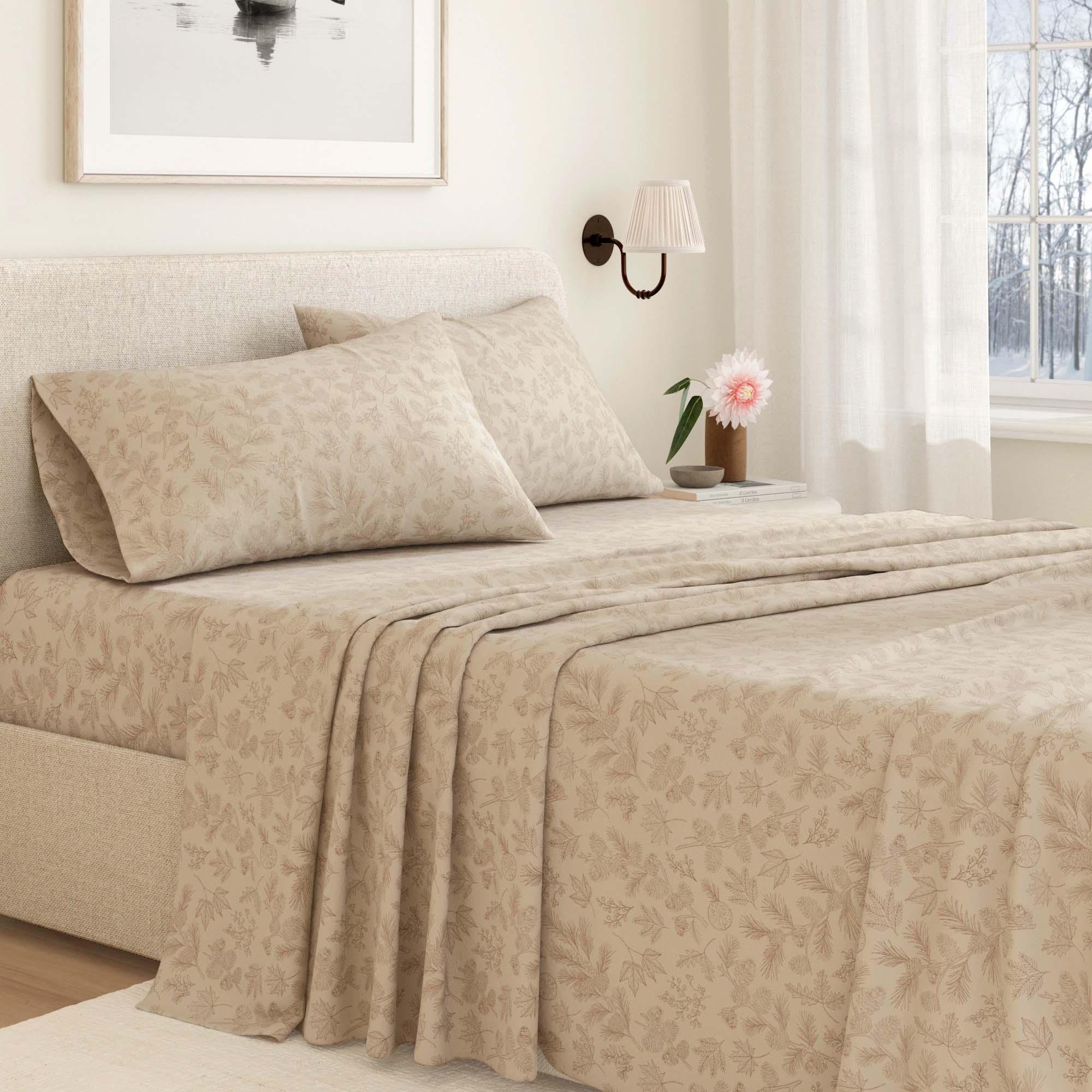 Beige bedspread on a neatly made bed in a bedroom with a lamp and window in the background.