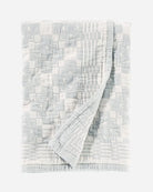 Textured light blue and white quilt with a geometric pattern on a white background