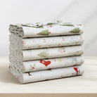 Stack of folded fabric with Christmas-themed patterns on a light surface.