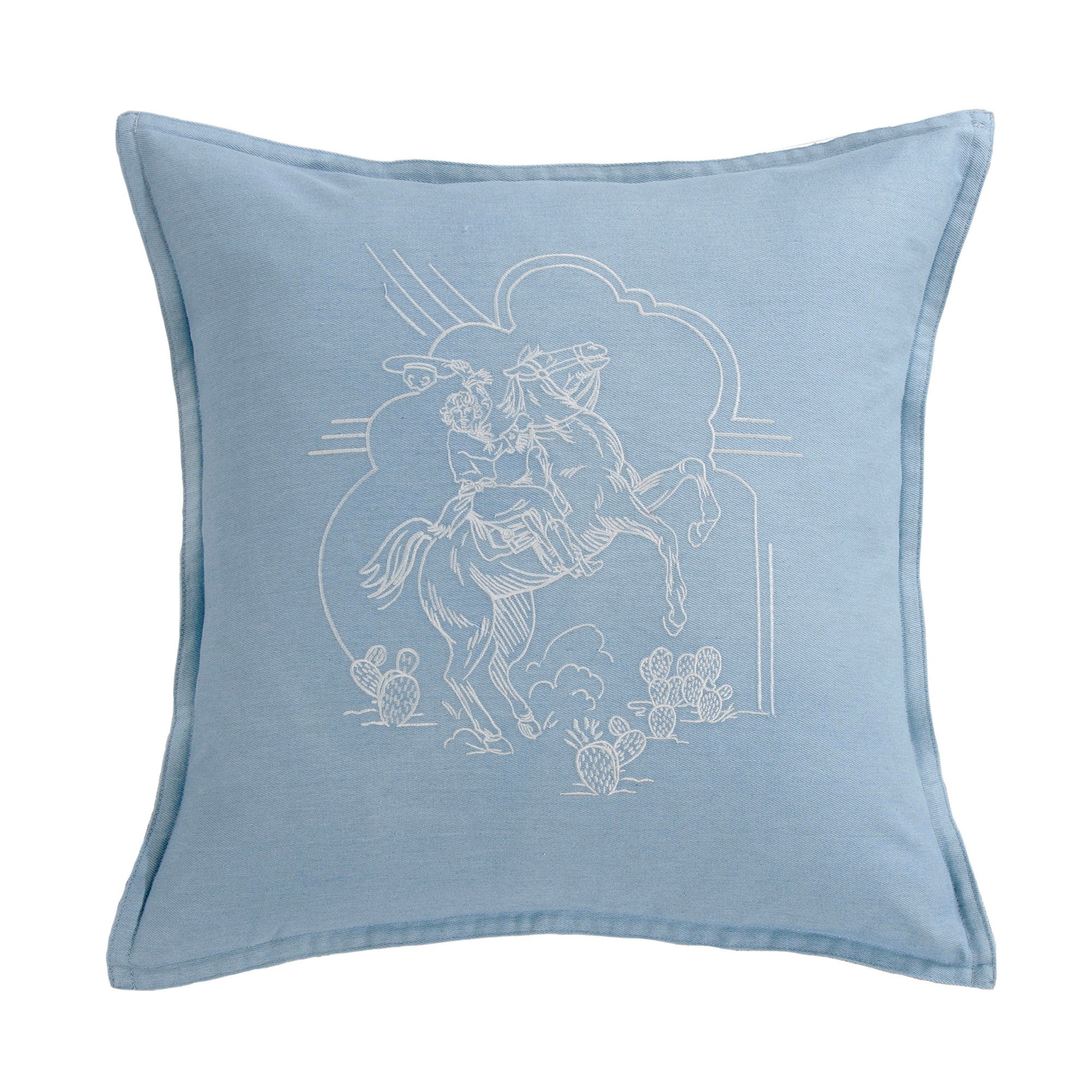 A square light blue throw pillow featuring a white embroidered illustration of a cowboy riding a horse with cacti and arches.