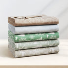 Stack of folded fabric sheets with different patterns on a white surface