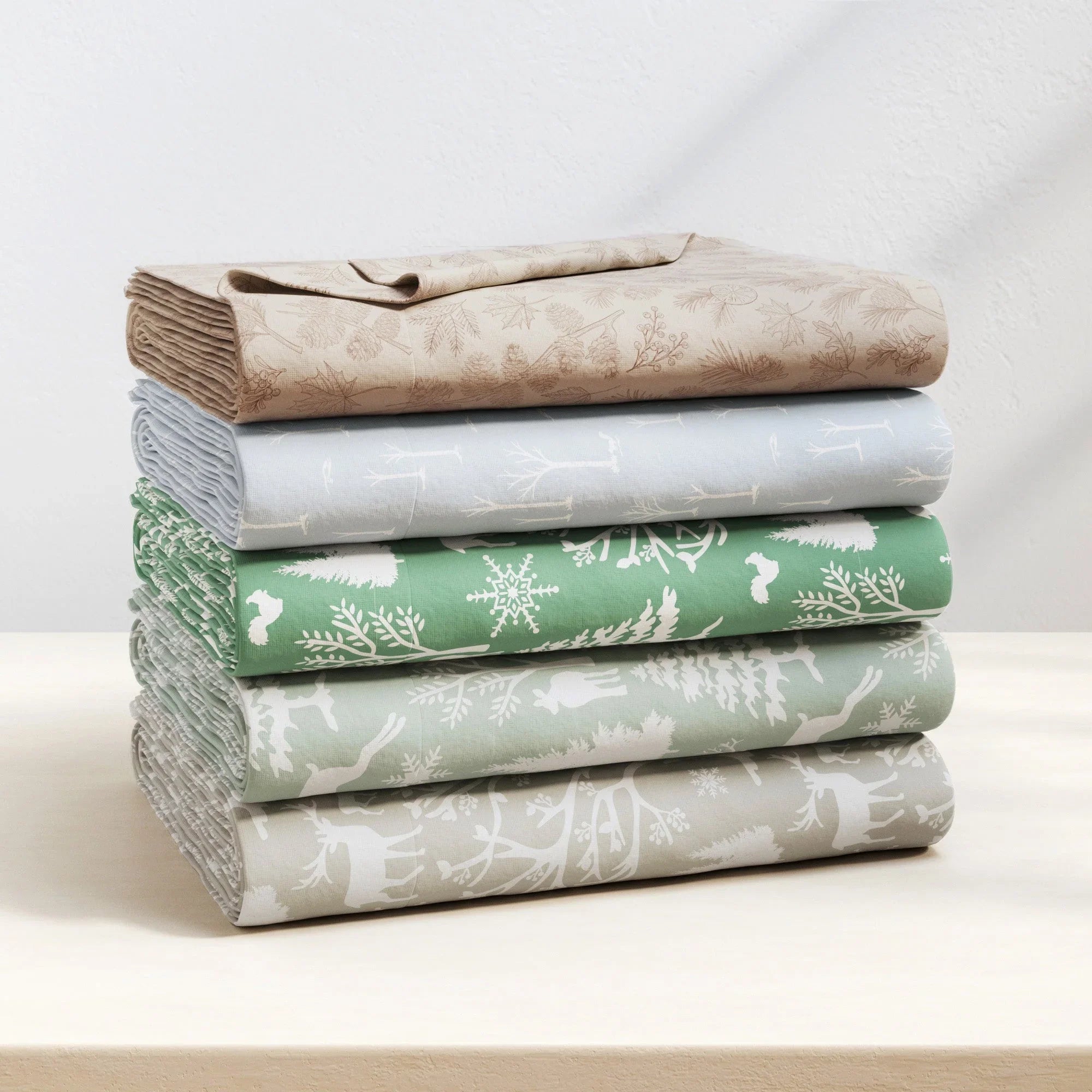Stack of folded fabric sheets with different patterns on a white surface