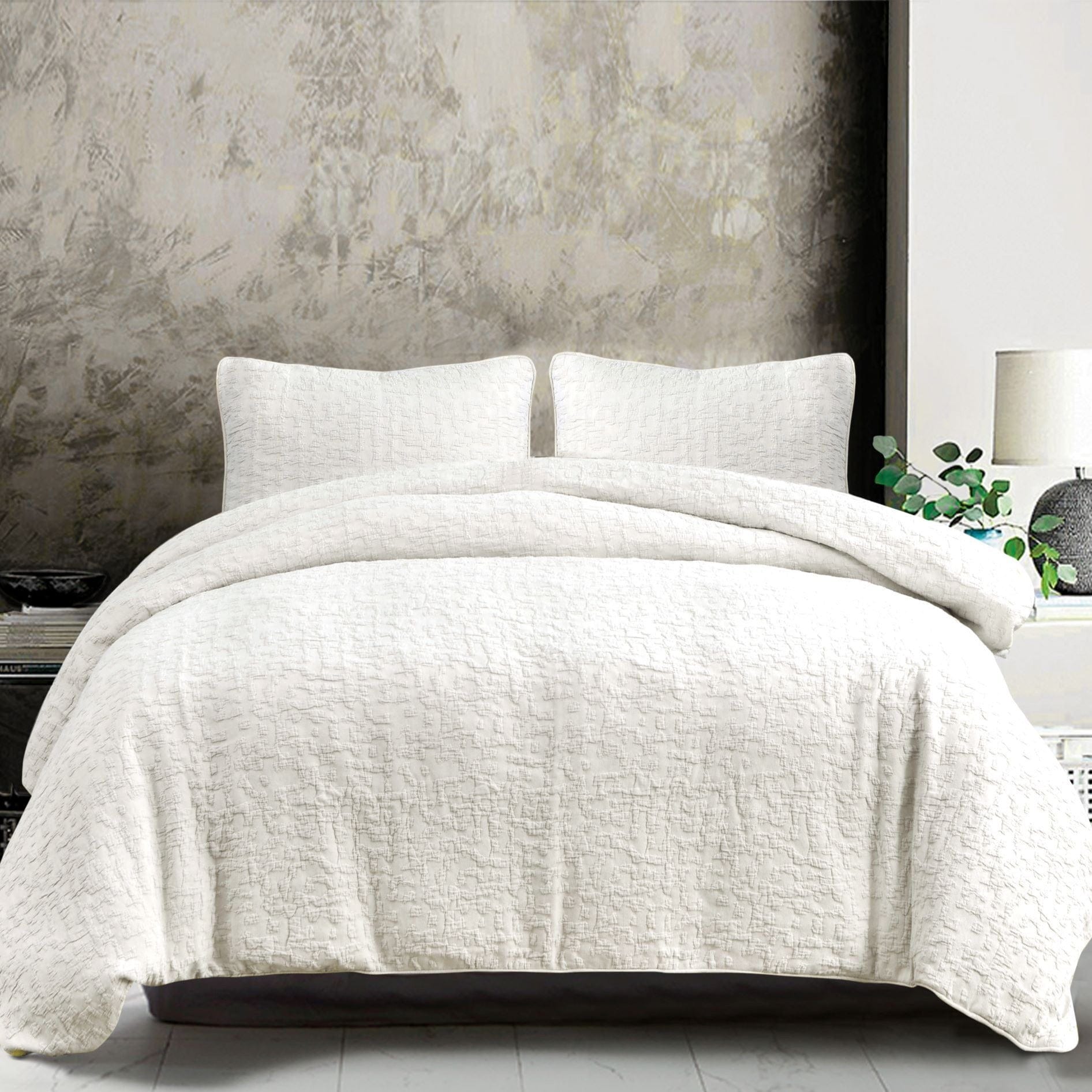 White textured comforter set on a bed with a neutral wall background