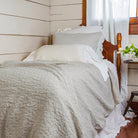 Bed with gray bedding and white pillows in a bedroom setting.