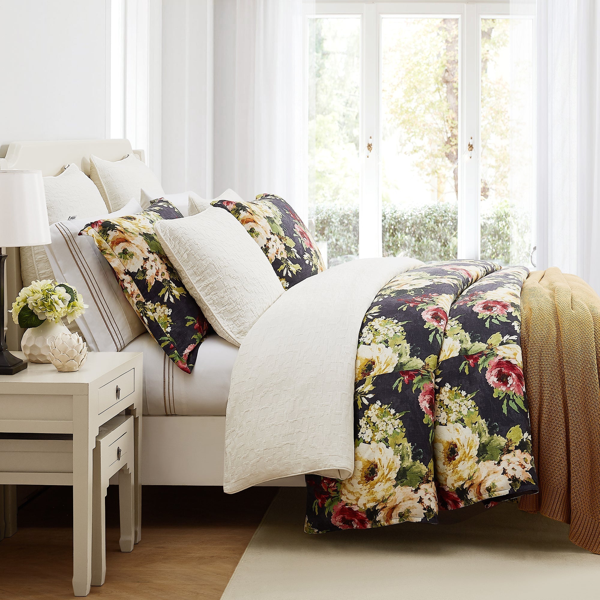 Floral-patterned comforter on a bed in a bright bedroom with natural light.