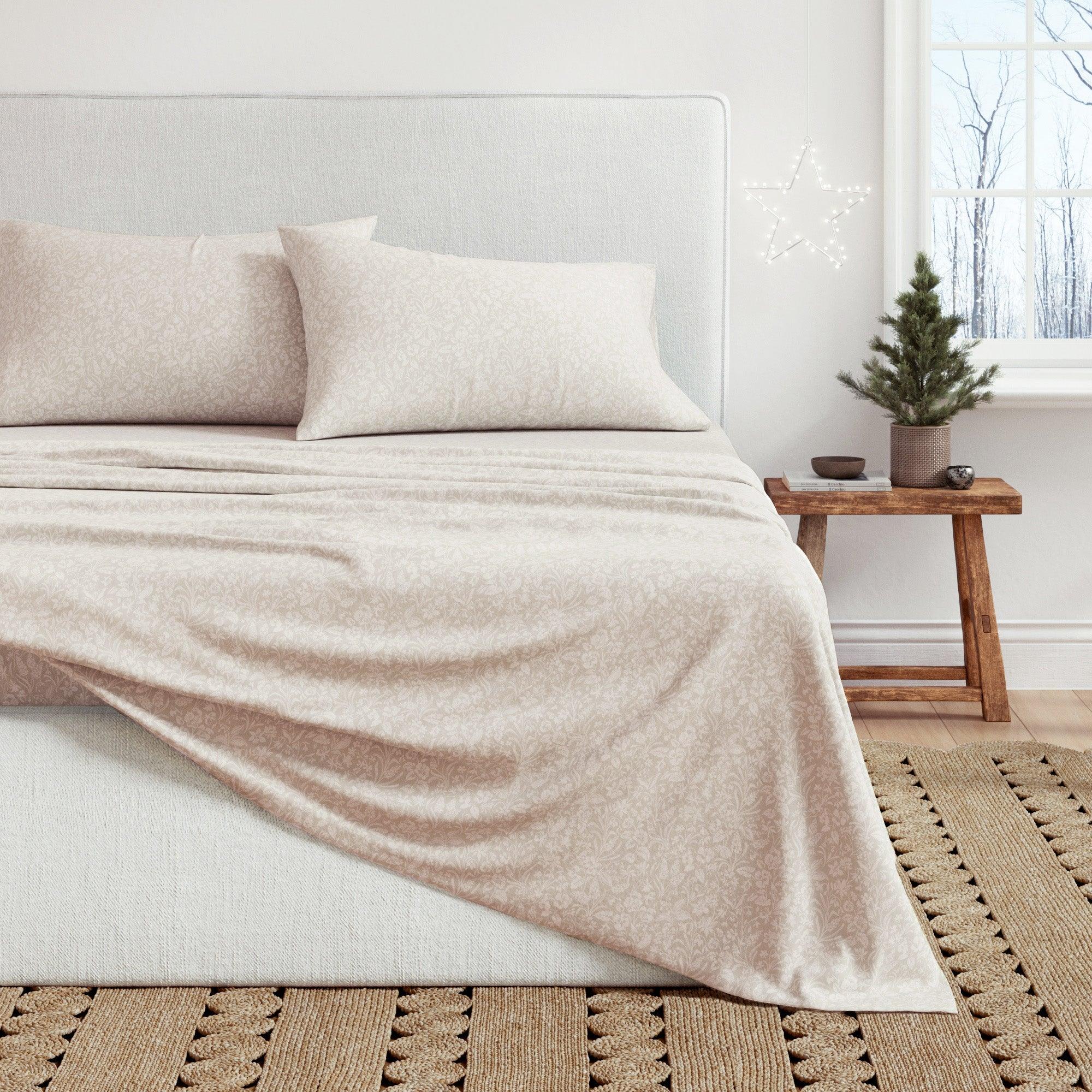 Neatly made bed with beige floral pedals bedding in a bedroom setting.