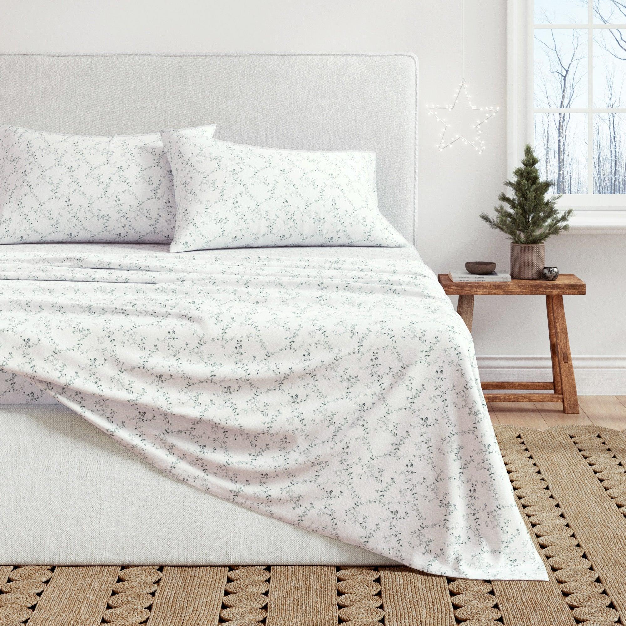 Bed with floral-patterned bedding in a room with a small Christmas tree.