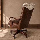 A rustic brown leather swivel office chair with a cowhide hair-on-hide backrest, set on a woven rug against a textured beige wall.