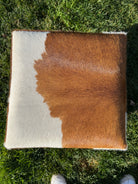 Brown and white cowhide cube ottoman top on feet with natural hide pattern in Western rustic, yet elegant style