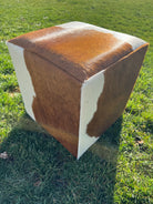 Brown and white cowhide cube ottoman on feet with natural hide pattern in Western rustic, yet elegant style