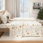 Bed with gingerbread-patterned bedding in a room with a Christmas tree and cityscape painting.