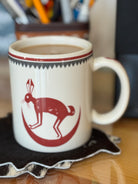 Mug with a red rabbit design on a coaster, filled with a beverage - Your Western Decor