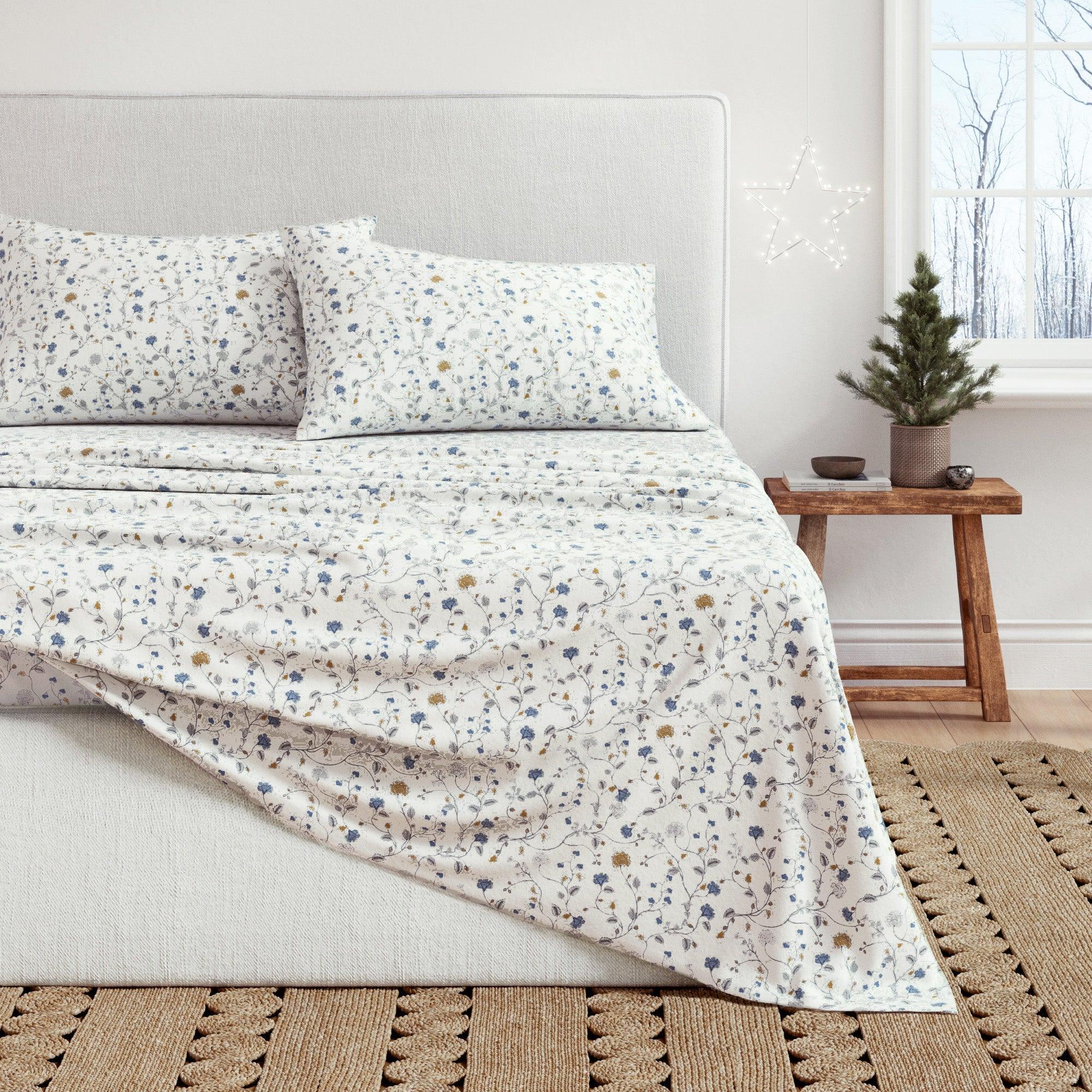Floral patterned bedding set on a bed in a bedroom with a small Christmas tree.