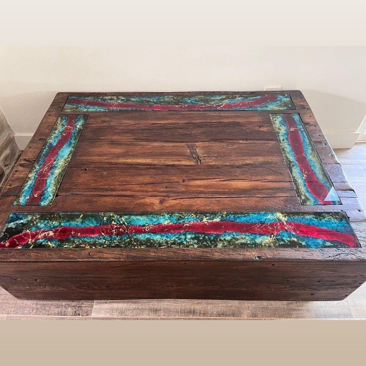 A rustic rectangular wooden coffee table with a dark brown wood grain finish and colorful resin inlay accents in red, turquoise, and green on the top surface.