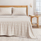 Beige Christmas animal print coverlet on a bed with matching pillows, wooden headboard, and side table.