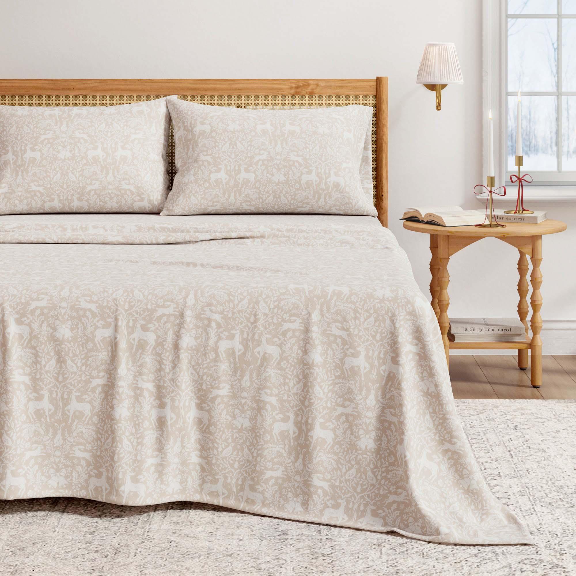Beige Christmas animal print coverlet on a bed with matching pillows, wooden headboard, and side table.
