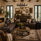 Modern western living room featuring a dark brown leather sectional sofa with rustic contemporary styling, southwestern accent pillows, a neutral tribal area rug, and curated western wall decor including a longhorn skull, horse artwork, and rope accents. Warm wood ceiling beams, black framed French doors, a stone fireplace, and layered natural textures create a cozy luxury ranch-inspired interior with upscale modern western design.