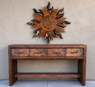 rustic metal sun wall art mounted above a western console table with wood frame and hammered copper drawer fronts in a ranch-style setting