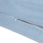 A close-up of a light blue denim pillow cover, showing a white metal zipper along the edge against a white background.