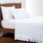 White sheet set with ruffled hem on a wooden bed
