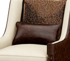 Brown leather pillow on a white armchair with a patterned brown backrest.