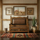 Wooden bench with leather seat in a room with framed pictures and a plant.