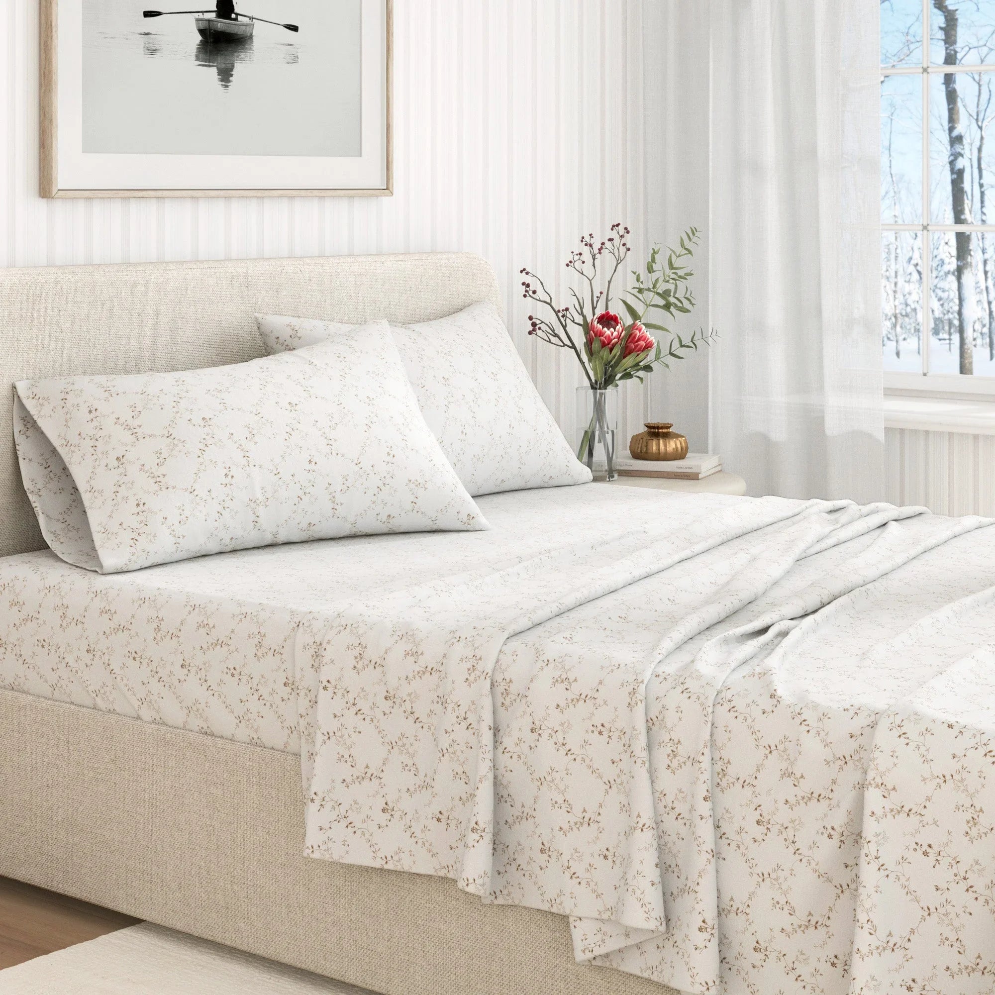 Floral patterned bedding set on a bed in a bright bedroom with a vase of flowers on the nightstand.