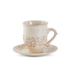 Cream-colored ceramic cup and saucer with intricate patterns on a white background