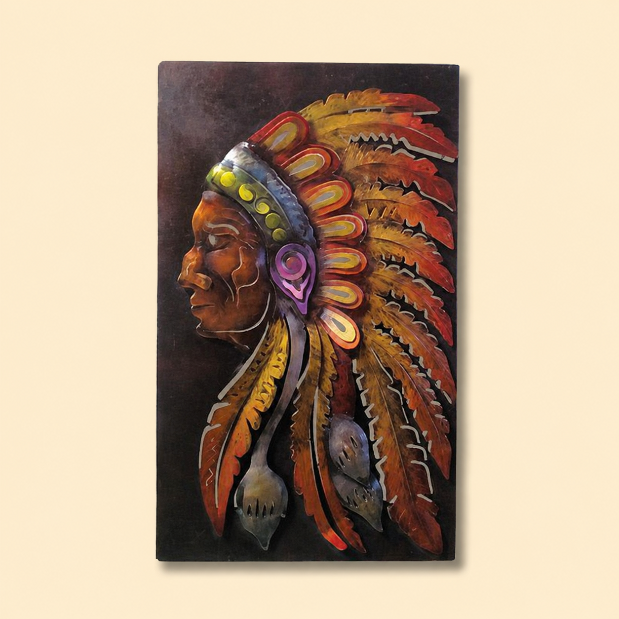 A vertical rectangular wall art piece showing a stylized profile portrait of a person wearing a large feathered headdress in warm red, orange, yellow, purple, and brown tones against a dark background, displayed on a light beige wall.