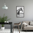 Modern living room with a horse print on the wall, gray sofa, and wooden chair - Your Western Decor