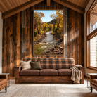 A large framed landscape art print of a river flowing through an autumn forest hangs on a rustic wood-paneled wall above a brown plaid sofa in a cozy cabin-style living room.