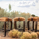Three stools with deer skin seats in a desert-like setting - Your Western Decor