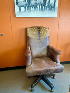 Brown leather office chair with deer headrest in front of an orange wall with a deer painting - Your Western Decor