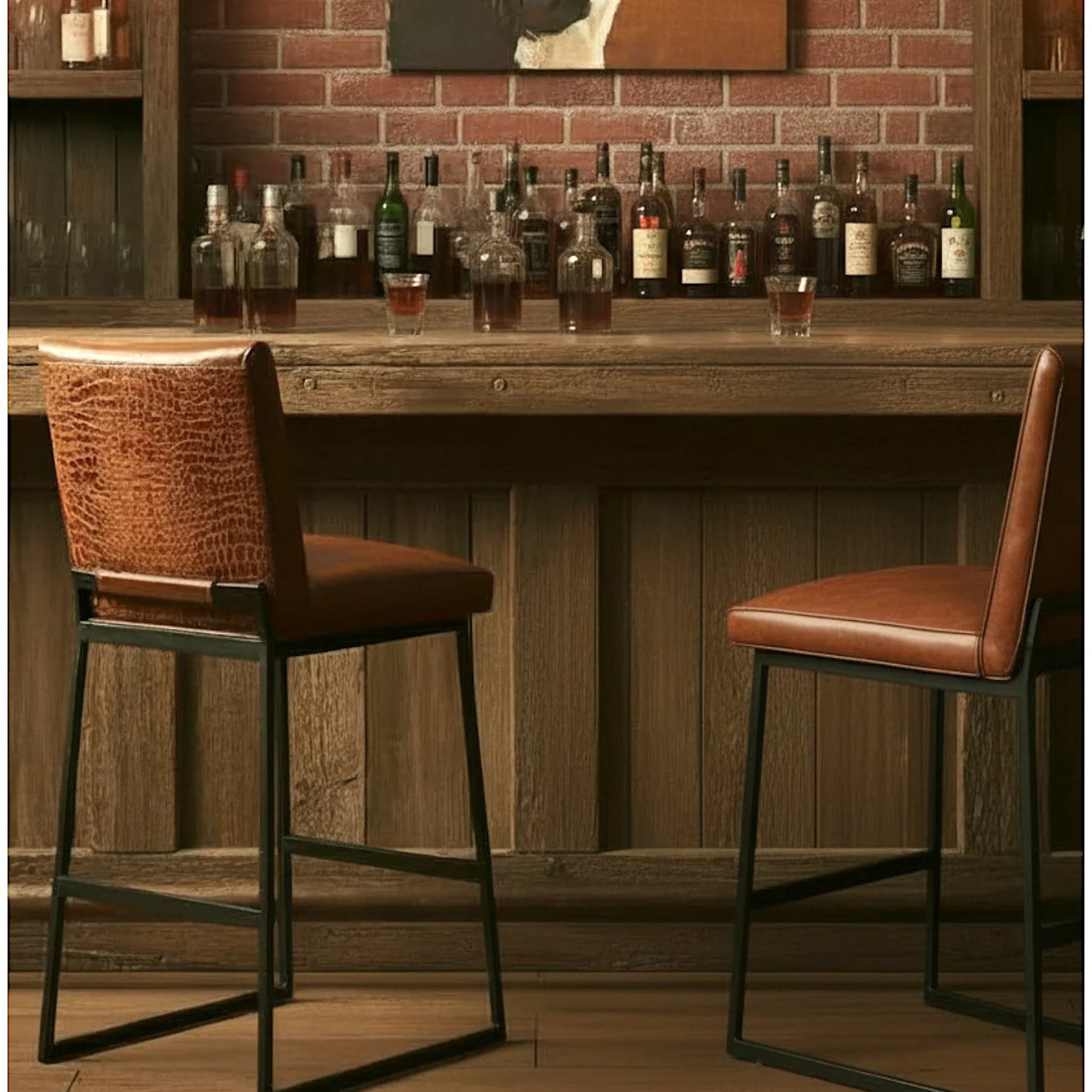 Two bar stools with brown leather seats and textured backs, set in front of a rustic wooden bar counter with liquor bottles and a brick wall background.