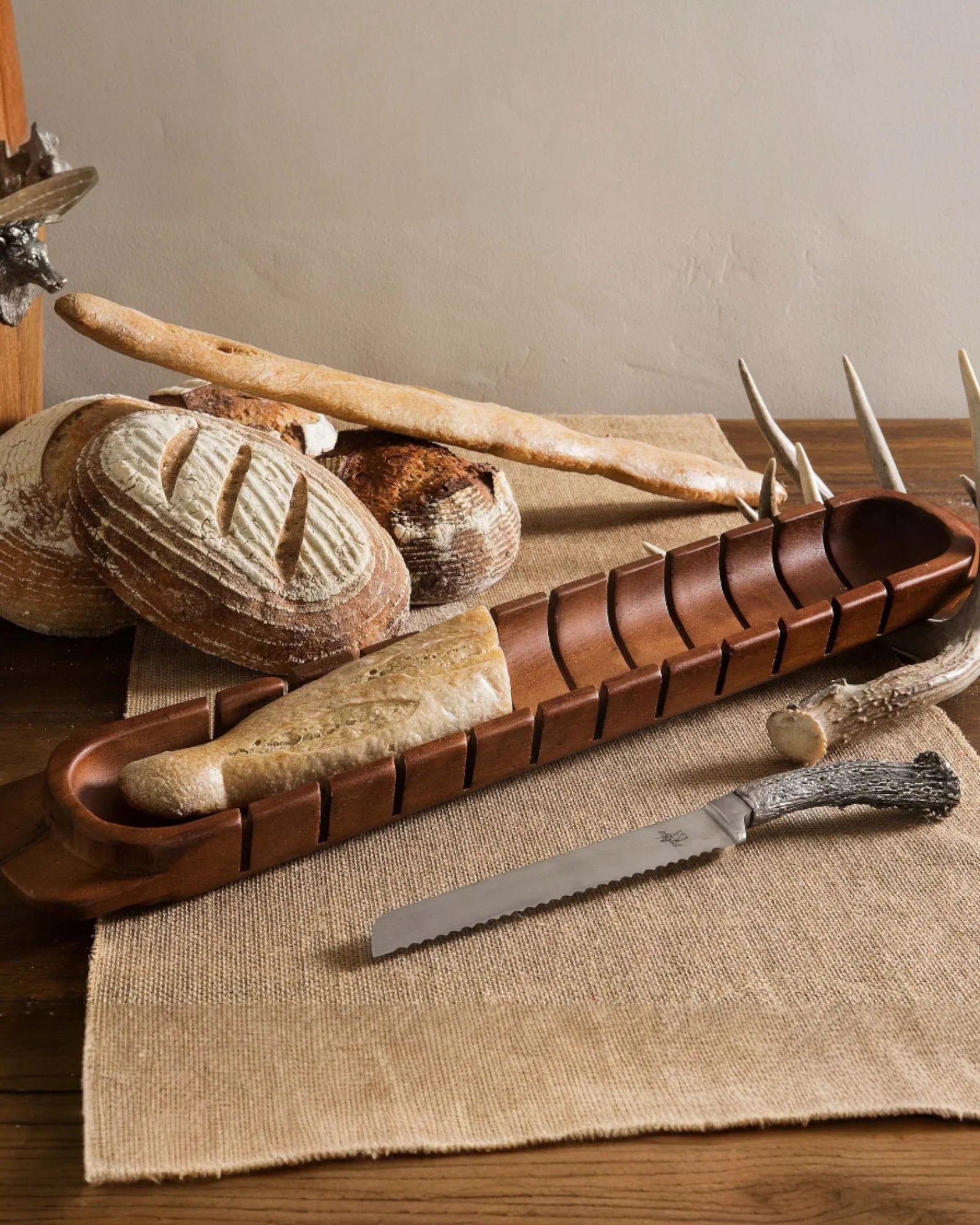 Wooden bread board with bread and a knife on a rustic wooden surface