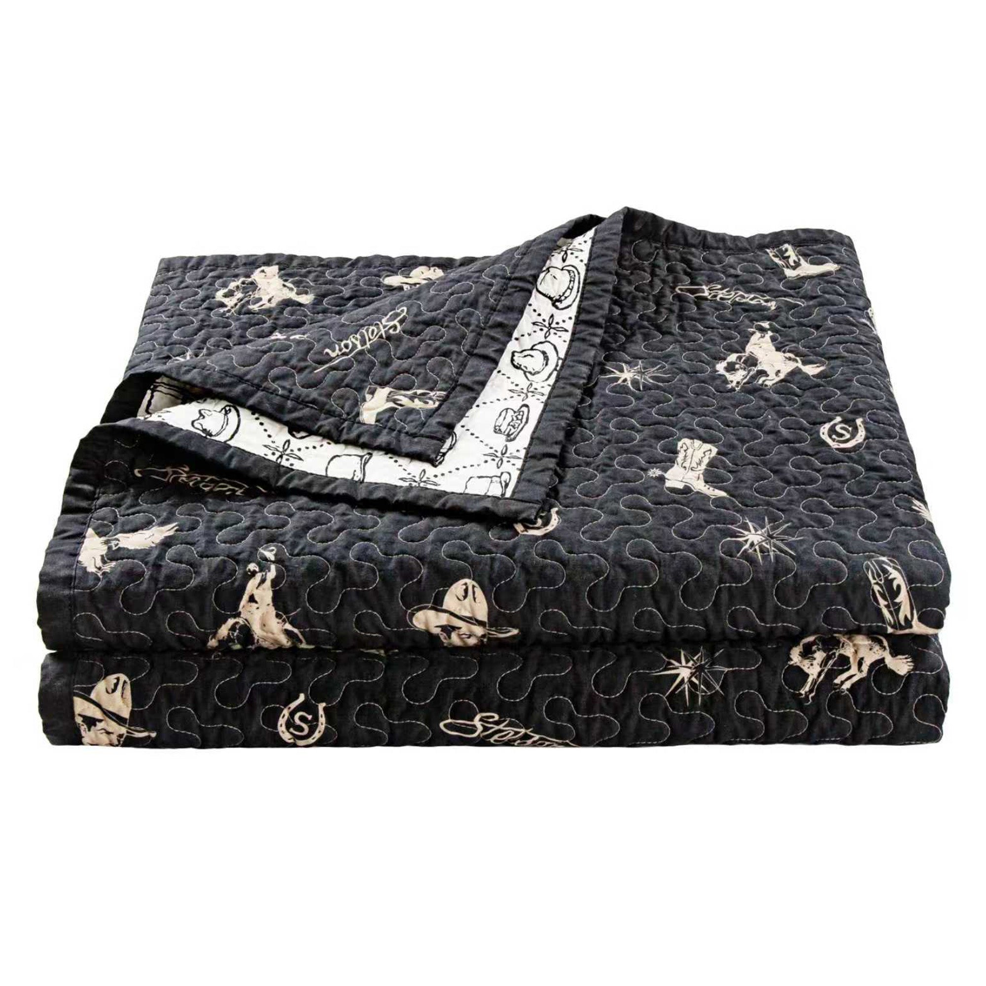 Black quilt with cowboy-themed pattern on a white background