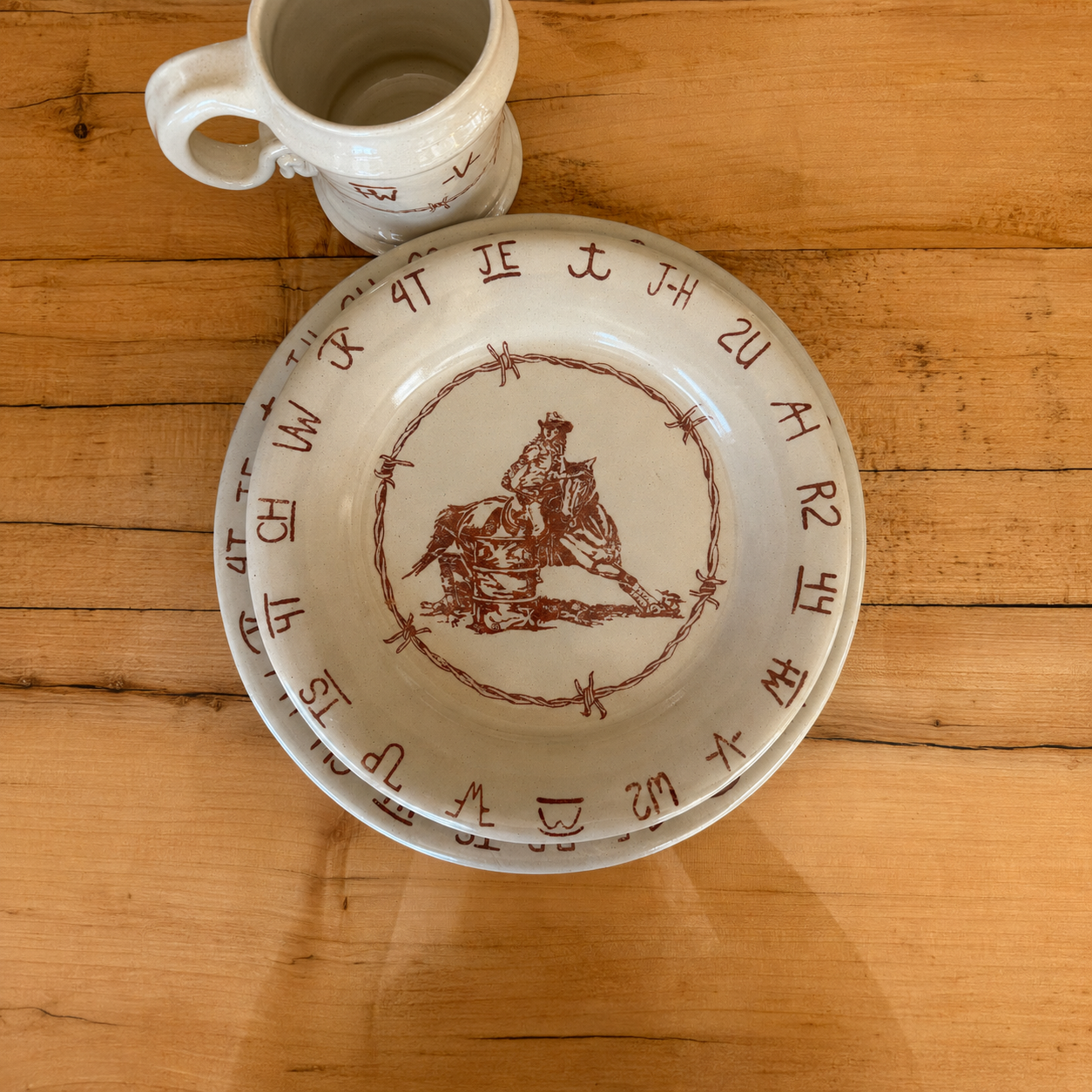 Blue Mountain Brands plates and mug featuring authentic ranch brands, barbed wire and rodeo imagery. Made in the USA