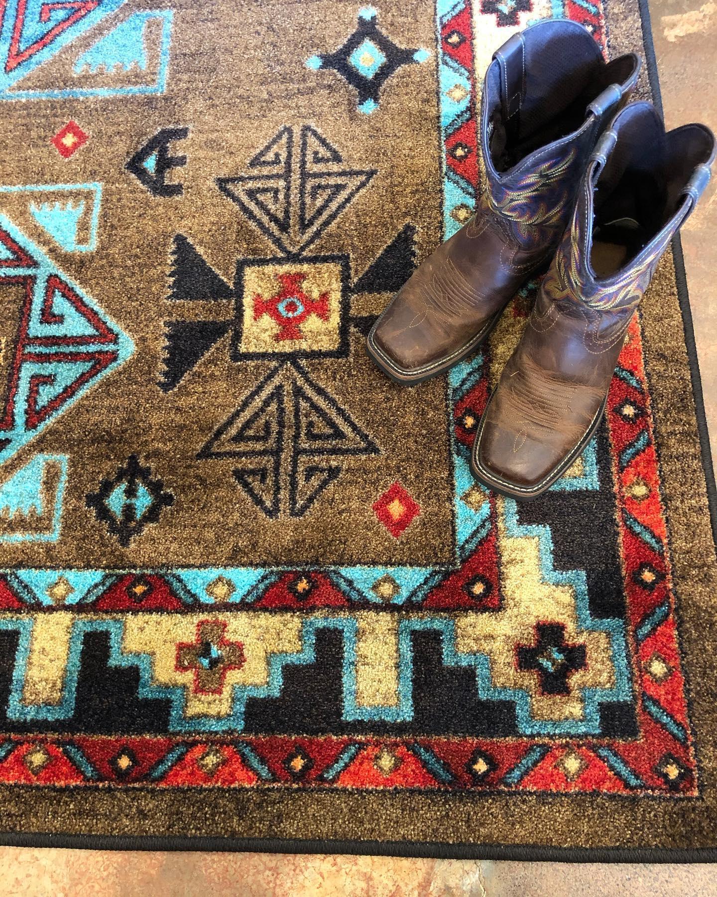 Pair of cowboy boots on Blue Zircon Southwestern Rug in geometric patterns of turquoise, red, beige and black over distressed brown background 