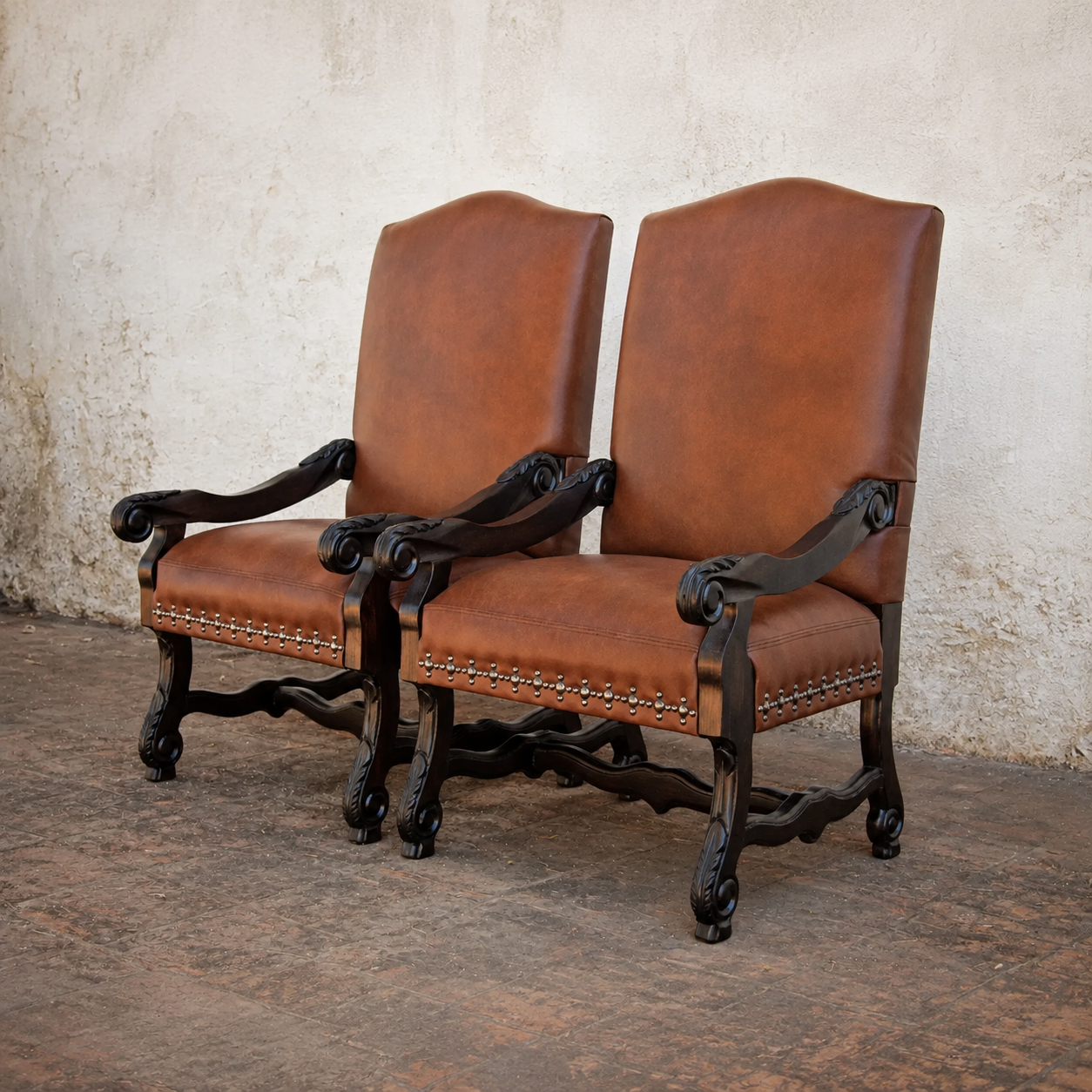 Two brown leather dining chairs with arm. Intricately carved wood frames and detailed nail tacking trim 