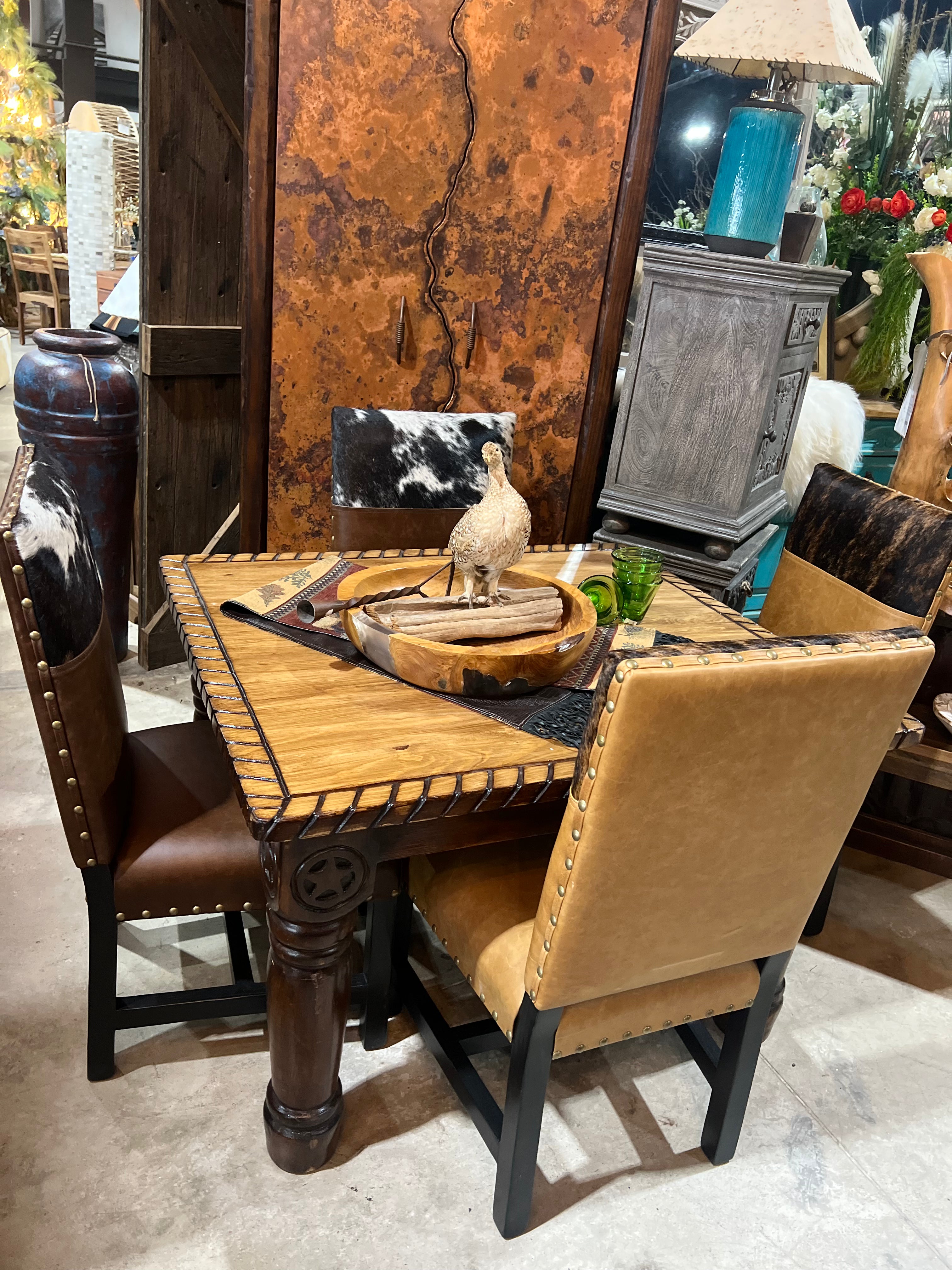 Dining table set with western leather chairs in a showroom setting - Your Western Decor