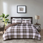 Brown plaid bedding set on a bed in a bedroom with a lamp and plant - Your Western Decor